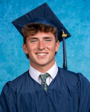 Smiling graduate in navy blue cap and gown with 2026 tassel.