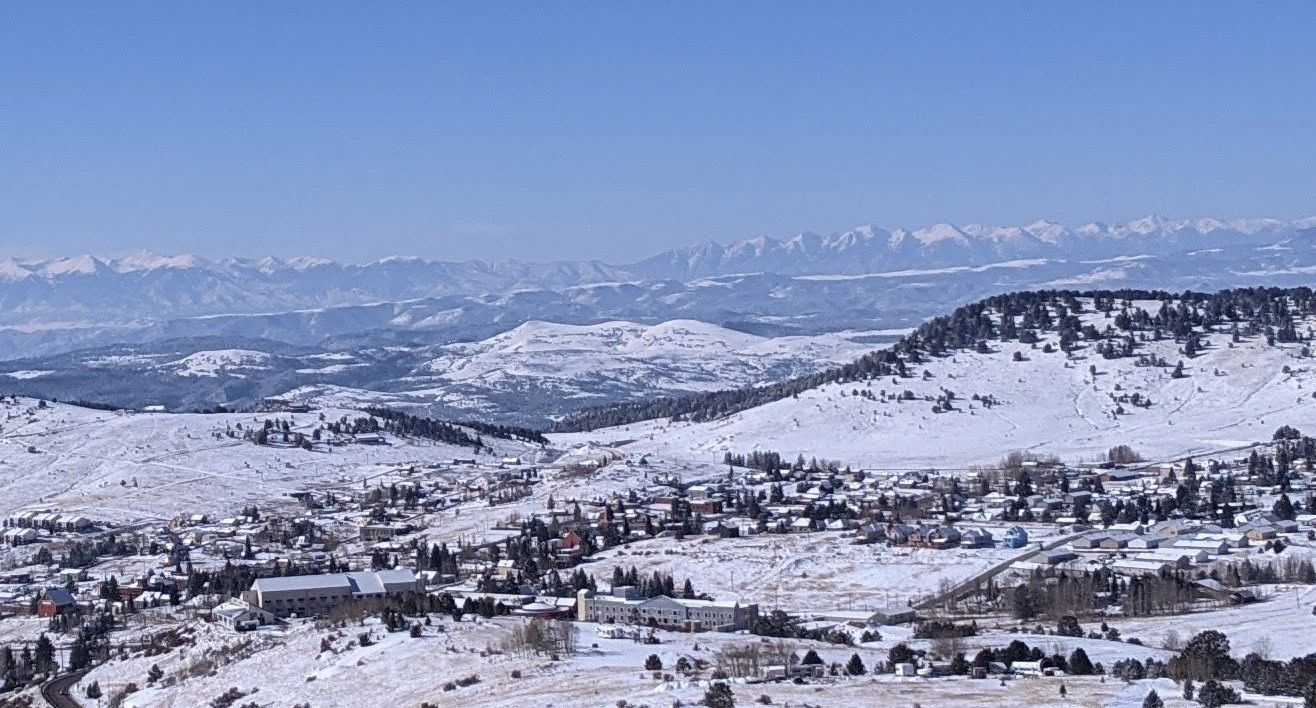 Snow-covered town nestled in mountainous landscape under clear blue sky.