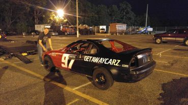 Man standing next to a race car at night.