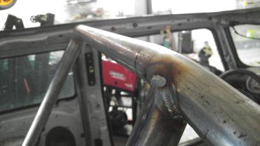 Close-up of a welded metal pipe joint on a vehicle frame.