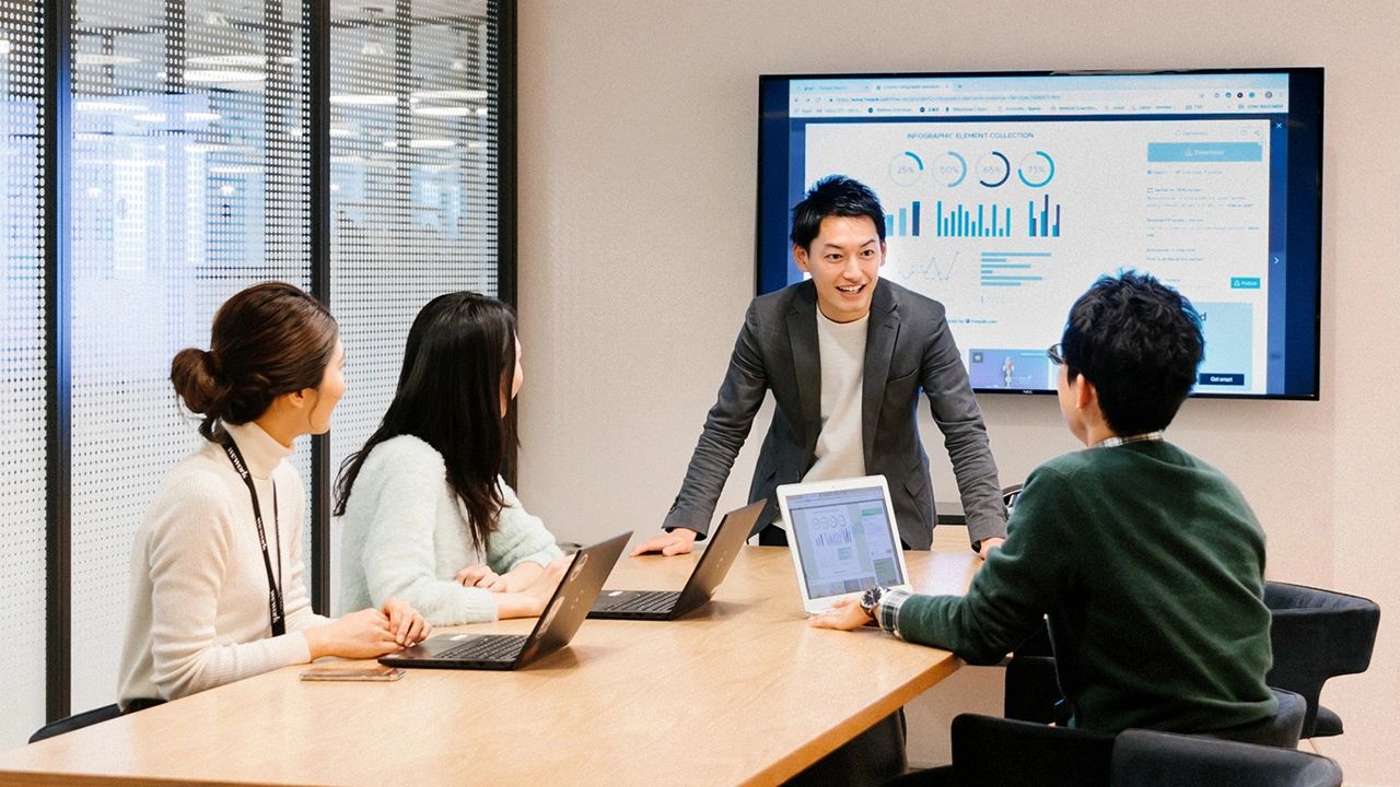 A business team discusses data charts during a meeting in a conference room.