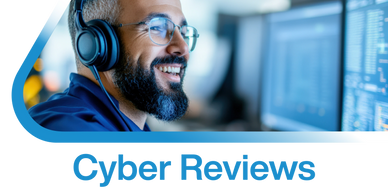 Man wearing headphones smiling while looking at computer screens.