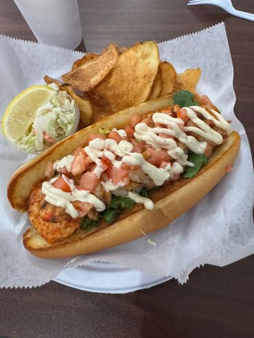 Shrimp po' boy sandwich with chips and cole slaw.