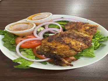 Grilled fish served on a bed of fresh salad with onions, tomatoes, and lettuce.