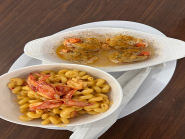 Macaroni and cheese with lobster claws and baked stuffed shrimp on a white plate.