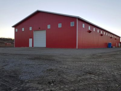 Large red metal building on a gravel lot at dusk.
