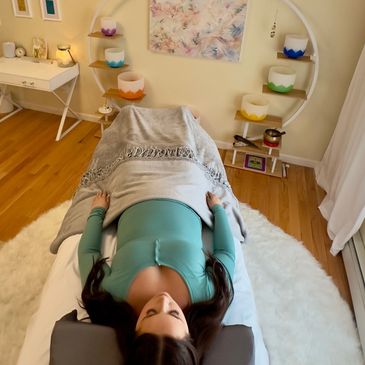 woman laying on massage table, sound bowls in background