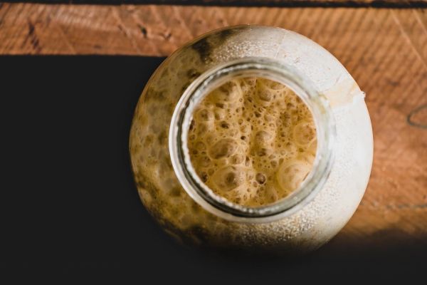 Top view of a bubbling sourdough starter in a glass jar.
