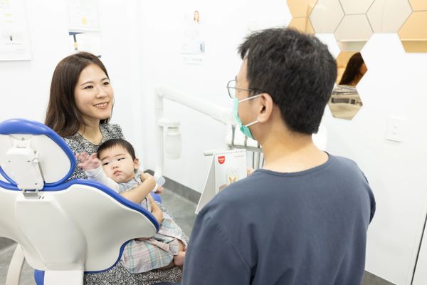 Patient with baby on dental chair getting explanation from Dr Terry Pu