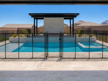 Black removable mesh pool safety fence with a centered locking gate surrounding a backyard swimming