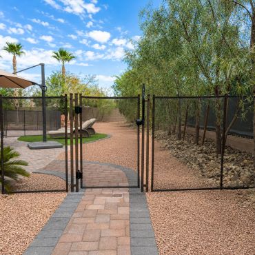 Black removable mesh pool safety fence with a locking walk-through gate installed across a landscape