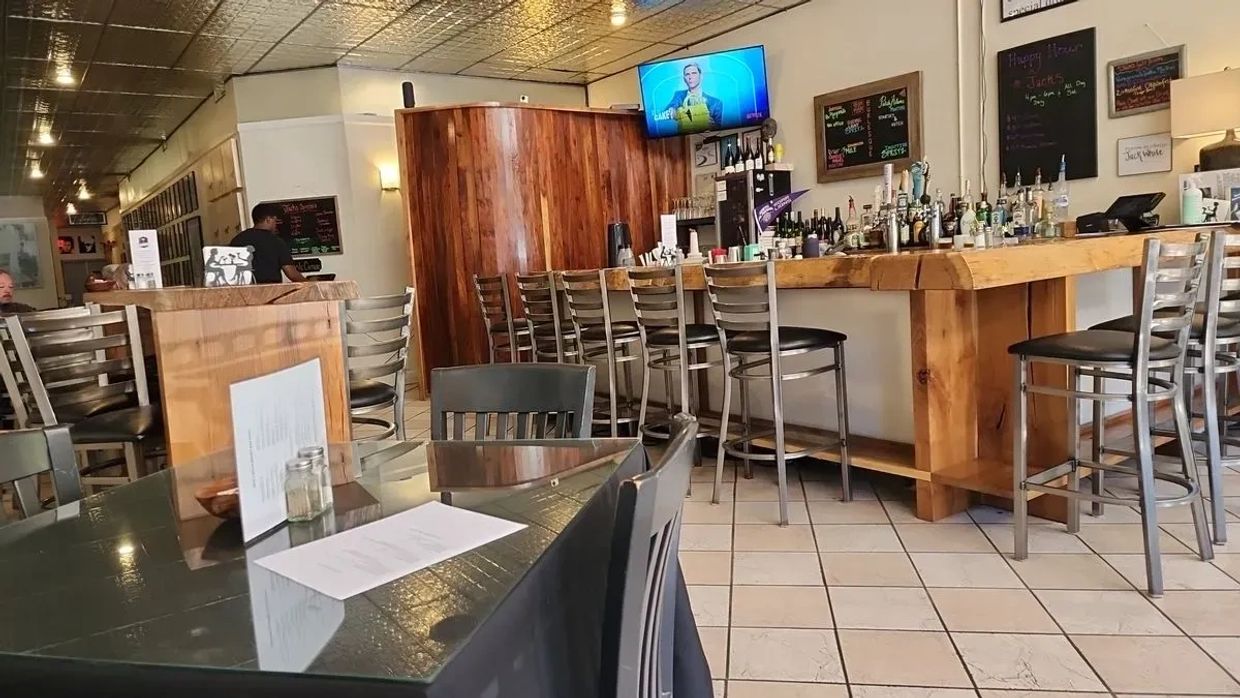 Cozy bar area with wooden furniture and a TV on the wall.