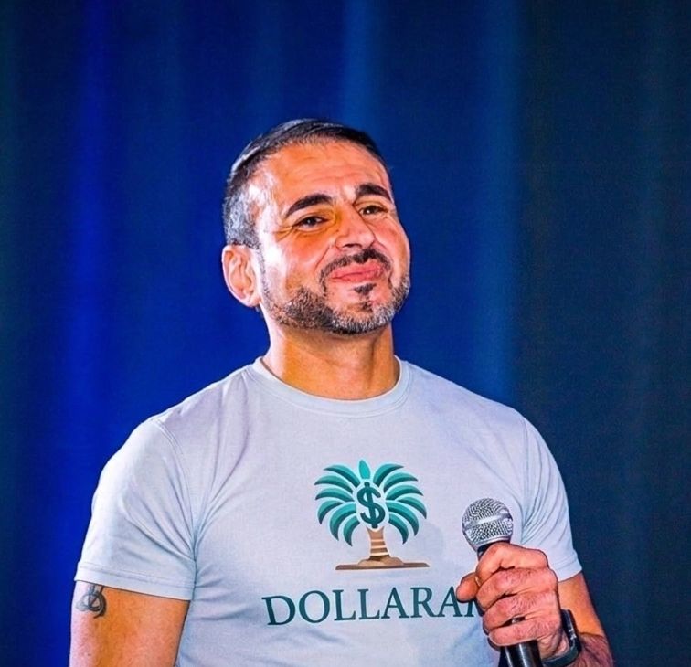 Man holding microphone wearing a Dollarama t-shirt, smiling.