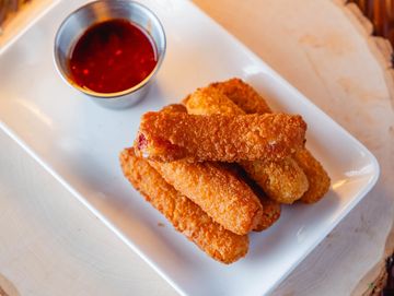 Crispy fried mozzarella sticks served with a side of marinara sauce on a white plate.