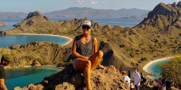 Kirsten sitting atop a mountain with beautiful beaches in the background