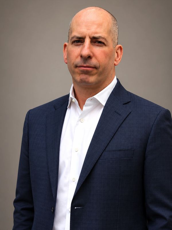 Confident man in a navy blue suit and white shirt.