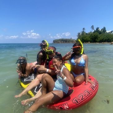 Family of 5 with snorkels on their faces sitting on a water tube  getting ready to go snorkeling.