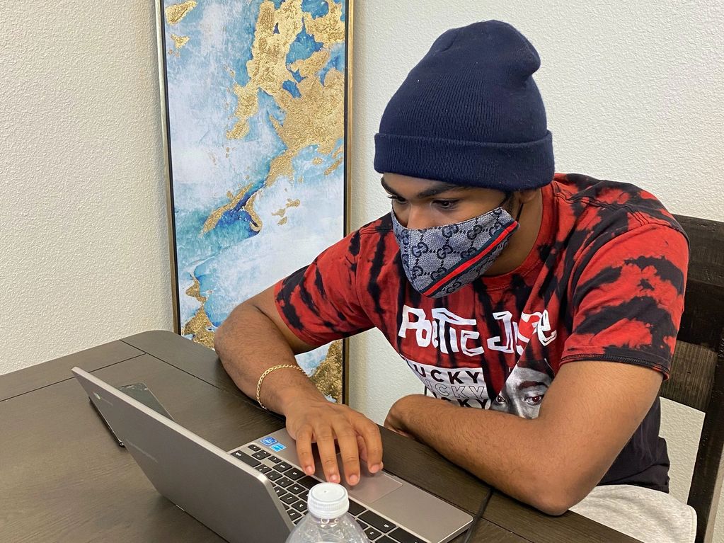High School Male Senior sits at the computer to graduate after a mishap