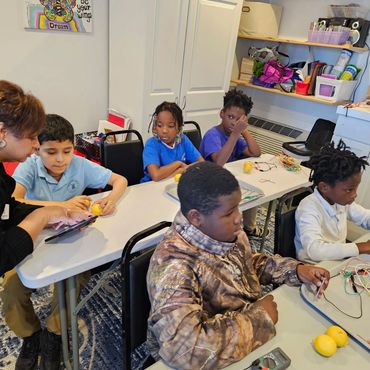 A class of Dominion Youth participating in. a science lab making batteries out of lemons.