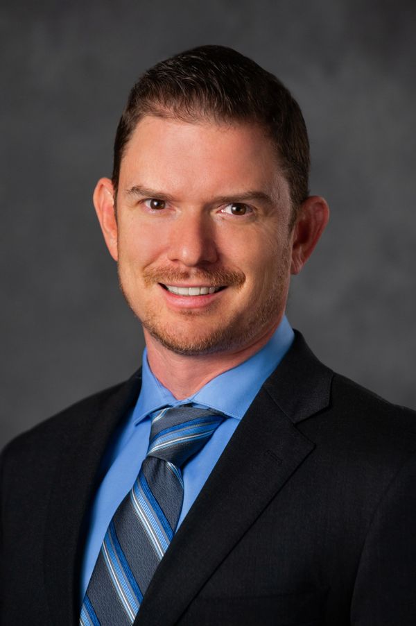 Professional man in a suit and blue tie smiling.