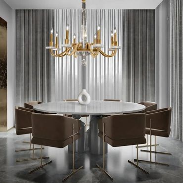 Modern dining room with round white table, brown chairs, and gold chandelier.