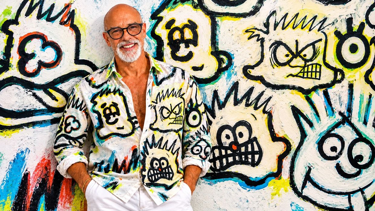 Man posing in front of cartoon art wall wearing matching cartoon shirt.