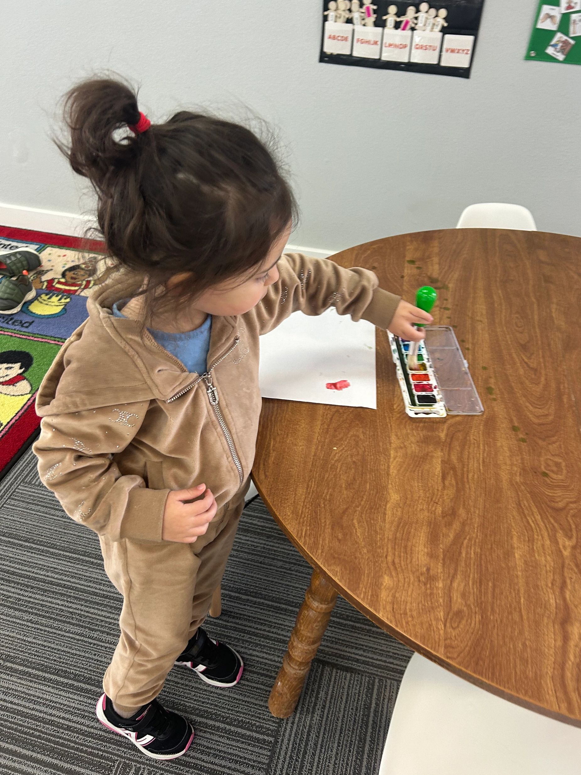 Child painting with watercolors during play-based learning at Empowered ABA.