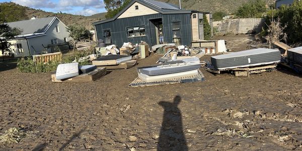 Flooded area with scattered mattresses and muddy ground.