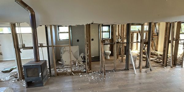Room under renovation with exposed wooden studs and an old wood stove.