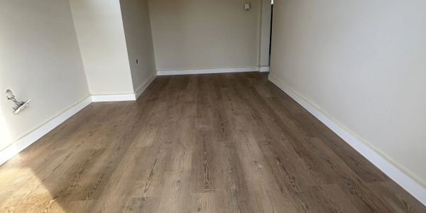 Empty room with wooden flooring and beige walls.