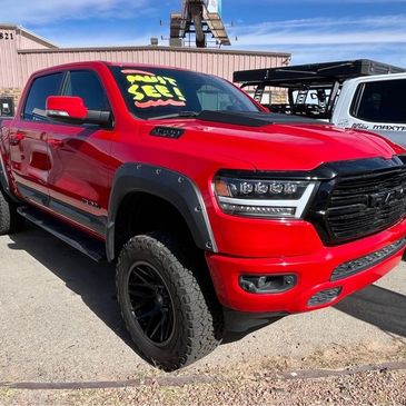 Bright red RAM pickup truck with aggressive tires and custom fender flares.