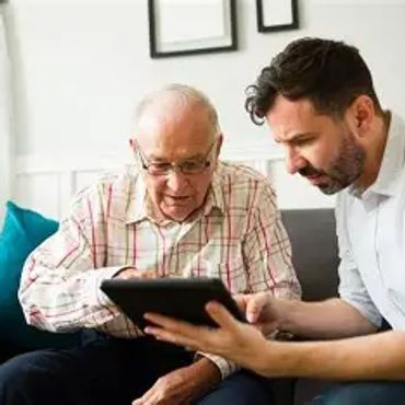 A young man shows an elderly man something on a tablet.