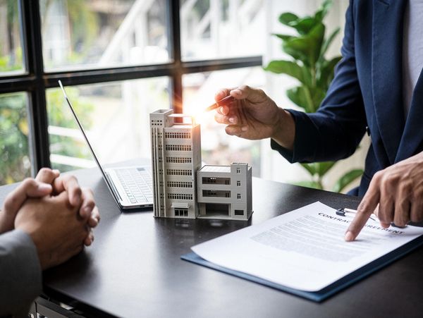 Real estate agents discussing a contract with a model building on the table.