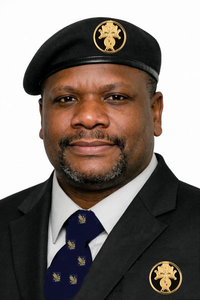 Homme en uniforme avec béret noir et insignes dorés.