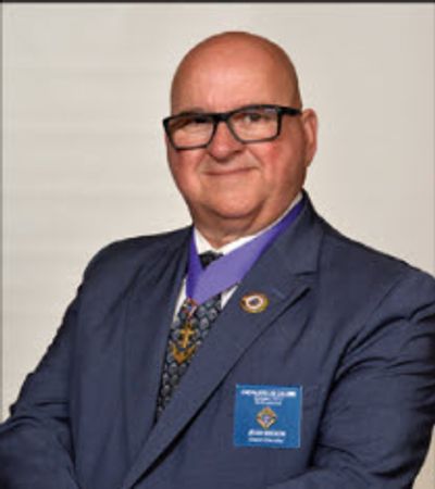 Homme en costume avec lunettes et médaille.