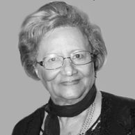 Black and white portrait of an elderly woman with glasses and a gentle smile.