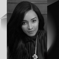Black and white portrait of a woman with long hair and a pearl necklace.
