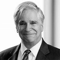 Black and white portrait of a smiling man in a suit and tie.
