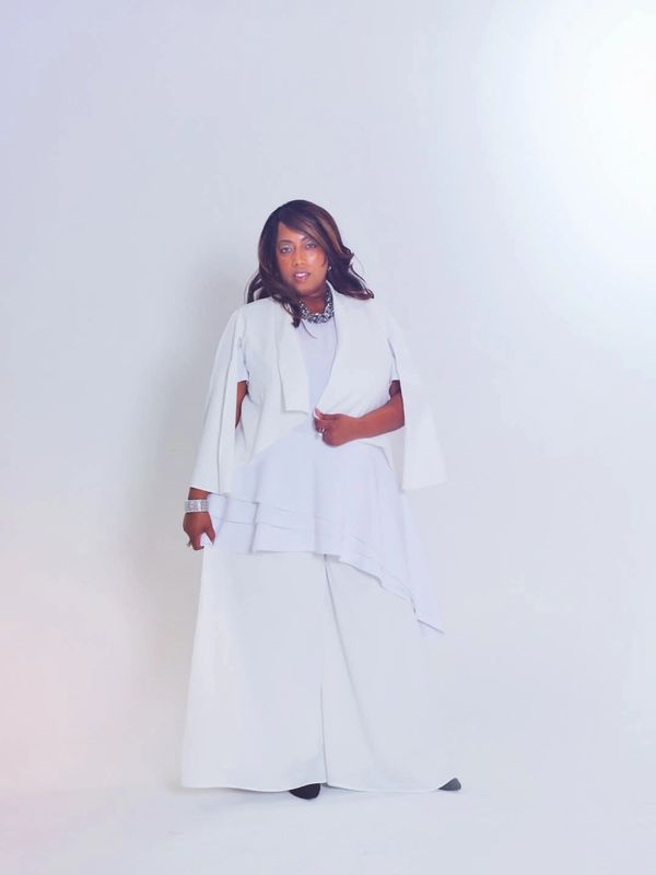 Woman wearing an elegant white outfit standing against a white background.