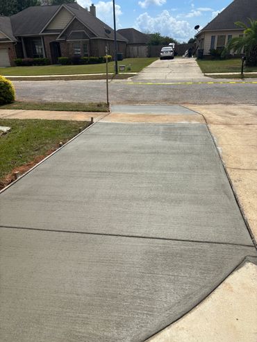 Freshly poured concrete driveway in a suburban neighborhood.