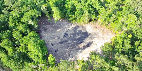 A cleared land area surrounded by dense green forest.