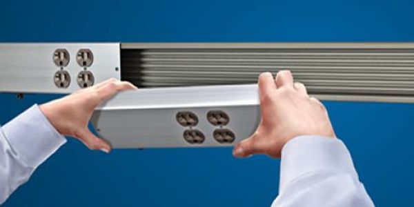 Hands installing a modular power outlet strip onto a track system.