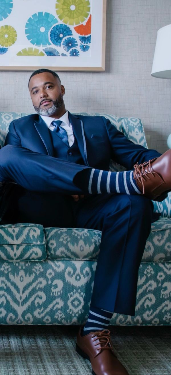 Man in suit lounging on a patterned couch.