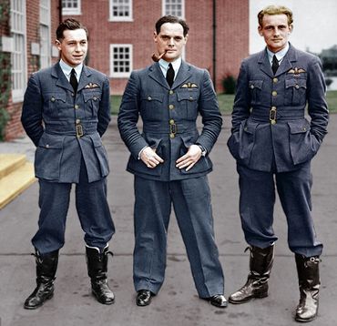 Three World War II pilots in uniform pose outdoors in front of a brick building.
