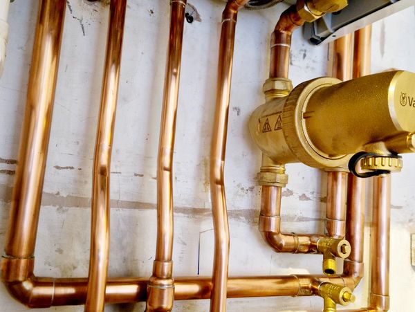 Cooper gas pipes installed on a wall underneath a heater