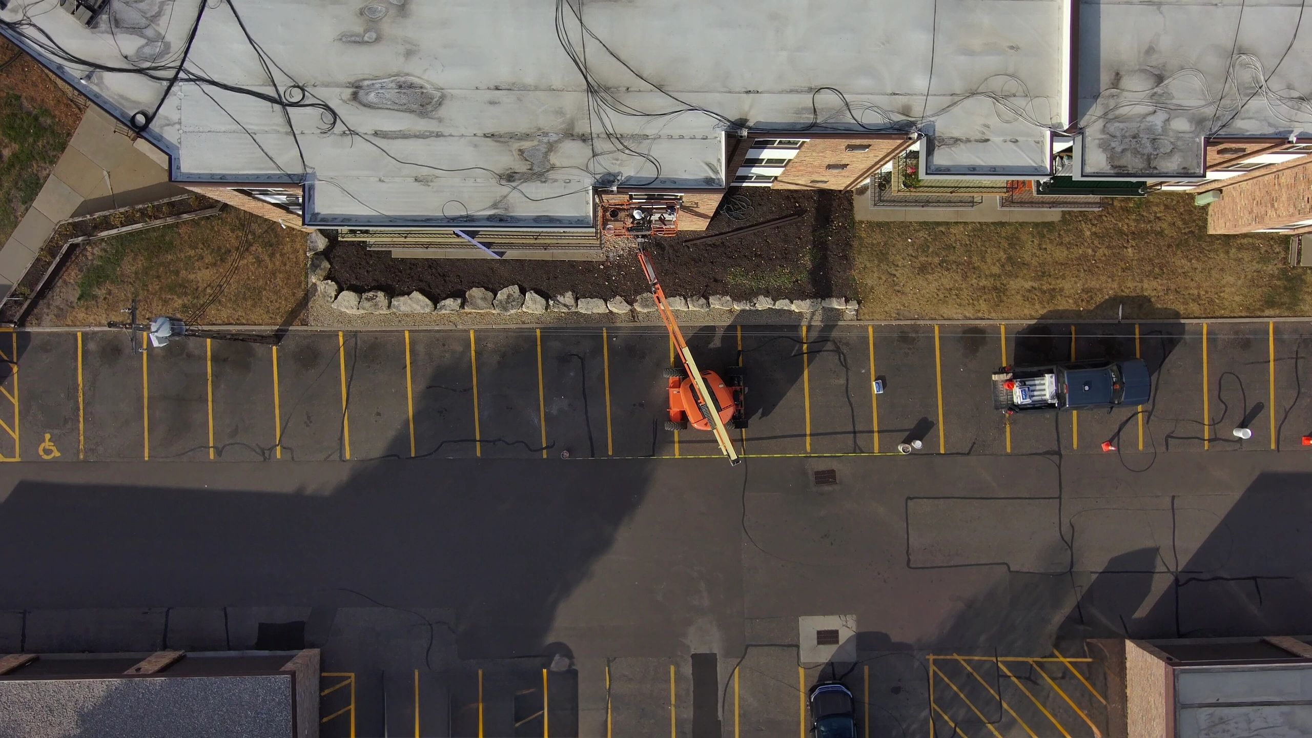 Aerial view of a parking lot with a cherry picker and a pickup truck.