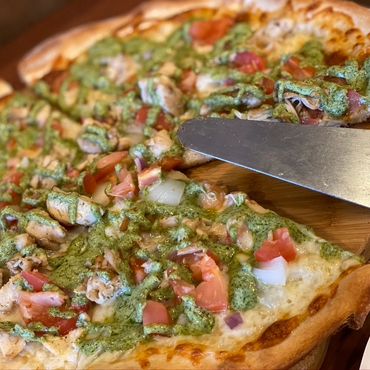 A delicious and freshly cut pizza with a knife resting on a wooden cutting board