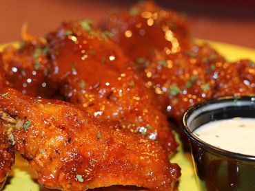 A plate filled with saucy chicken wings and dip, showcasing a delicious and appetizing presentation