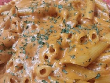 A plate of pasta topped with rich sauce and fresh herbs, elegantly presented for a delicious meal.