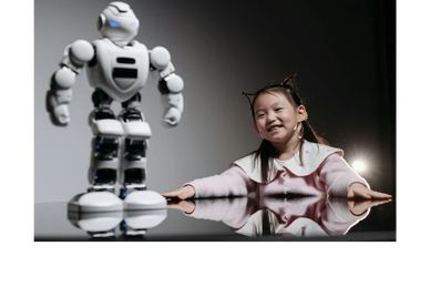 A smiling girl with cat ears looks at a white robot on a reflective surface.